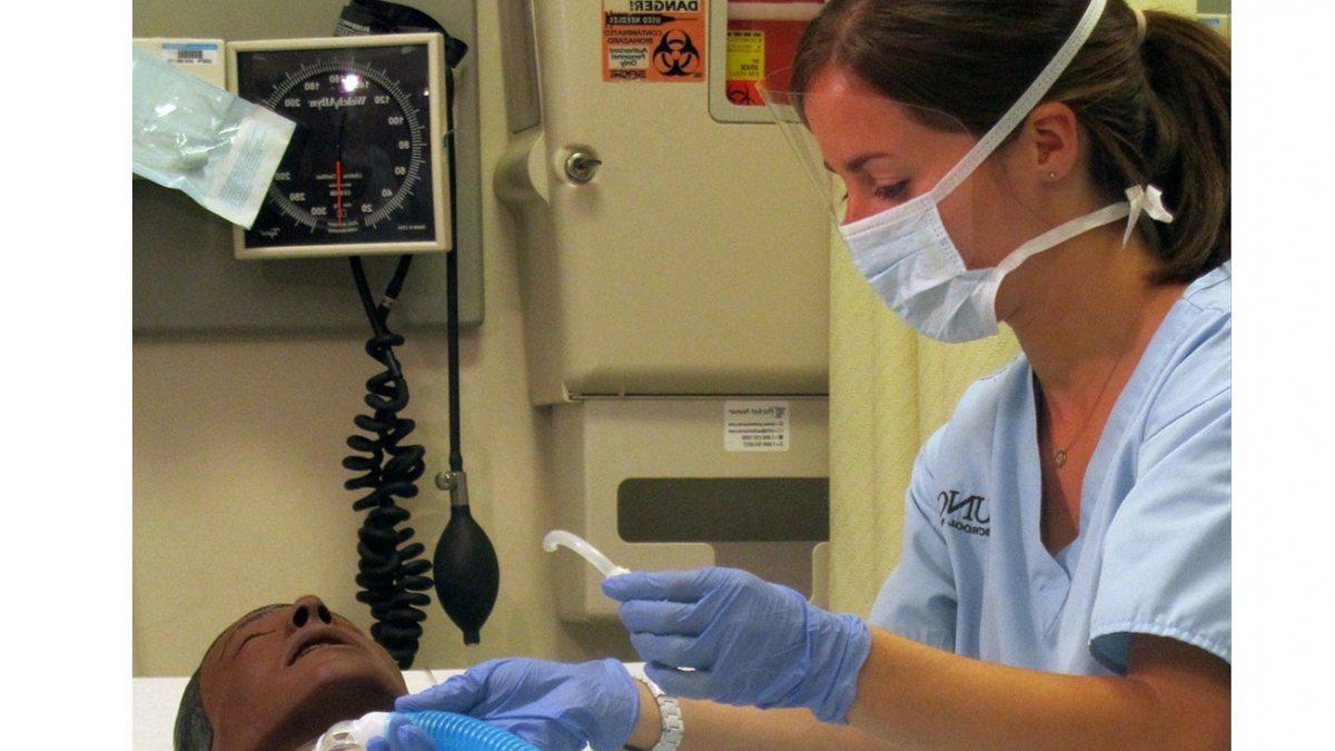 A nursing student works on a mock patient.